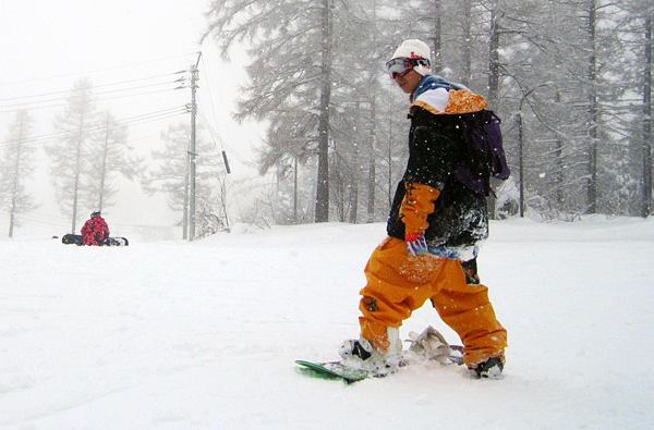 niigatatrip2 KCP students snowboarding on the slope while surrounded by snowflakes